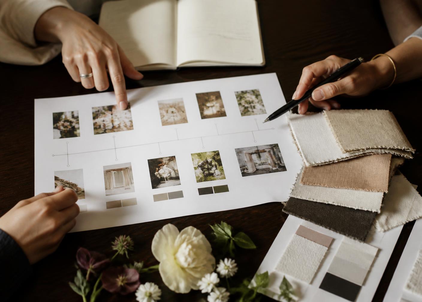 Mani al lavoro su una timeline stampata, moodboard, campioni di tessuto e fiori